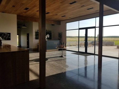 An open, ambient tasting room showcases the natural beauty surrounding the winery and leads to an open patio where guests can relax and enjoy their tasting experience.