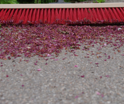 A red broom sweeping debris from a concrete floor to winterize